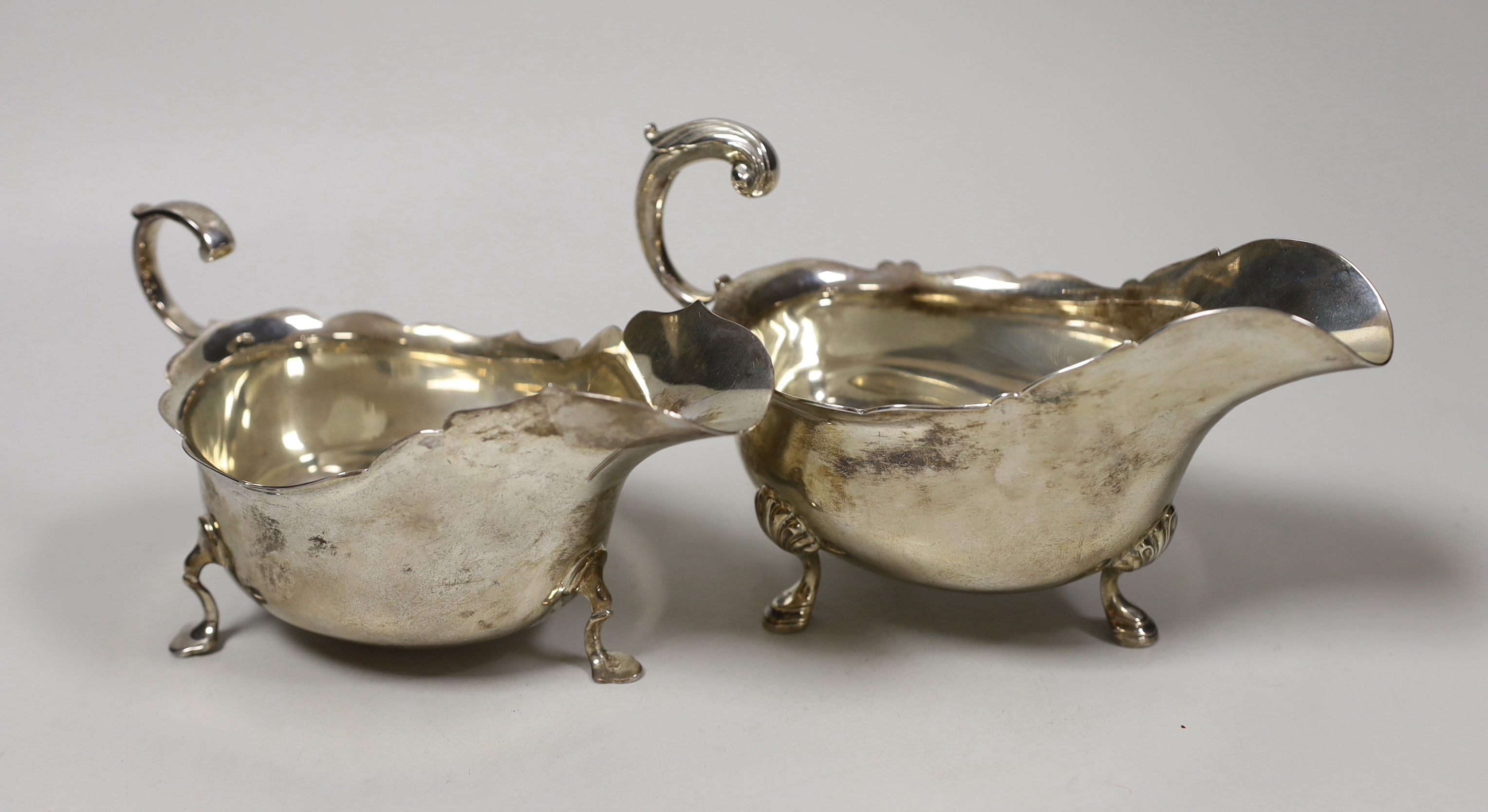 Two early 20th century silver sauceboats, with flying scroll handles, London, 1911 and Sheffield, 1907, 15.2oz.